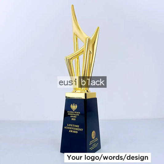 A trophy award with a polished gold abstract sculpture on a dark navy blue rectangular base, featuring gold lettering that reads 'GUANZHE PEACE HONORITY AWARD 2025' and 'LIFETIME ACHIEVEMENT AWARD'.